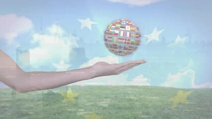 Poster - Holding globe with international flags, hand above grassy field and blue sky