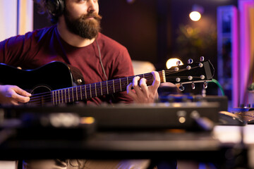 Leinwandbilder - Musician playing guitar and uses mixing gear to create new music, looking at daw software interface on computer. Producer recording soundtracks with electronic equipment, acoustical engineering.