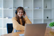 © Jirapong - Young woman enjoying a relaxing music break at her desk while using headphones, writing in a notebook, and working on her laptop for calm inspiration