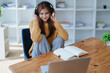 © Jirapong - Young woman enjoying a relaxing music break at her desk while using headphones, writing in a notebook, and working on her laptop for calm inspiration