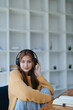 © Jirapong - Young woman enjoying a relaxing music break at her desk while using headphones, writing in a notebook, and working on her laptop for calm inspiration