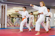 © JackF - Teenager children wearing karate uniform fighters poses in white kimono during group training in gym