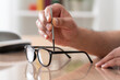 © cunaplus - Close up of man hands tightening screw on glasses with screwdriver on a desk at home.Male optician repairing and fixing eye glasses with screwdriver.
