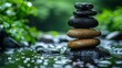 © Danila - Green leaves are scattered around a pyramid of Zen stones that has been placed on the water's surface, resulting in a serene and peaceful ambiance