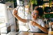 © Dusan Petkovic - Happy young interracial woman taking selfies with coffee in coffee shop.