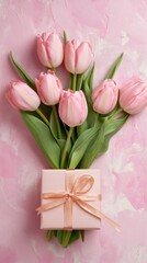 Poster - Beautiful bouquet of pink tulips lies on a textured pink surface, accompanied by a delicately wrapped gift box, creating a perfect mother's day scene