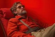 © Trionorejo - Man in sunglasses lounges on a red chair against a red background, relaxing in casual attire