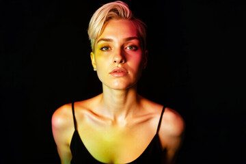 Poster - Portrait of a woman with short blonde hair under colorful creative lighting on a dark background, highlighting artistic mood and expression.