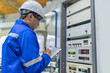 © reewungjunerr - Electrical engineer man checking voltage at the Power Distribution Cabinet in the control room,preventive maintenance Yearly,Thailand Electrician working at company