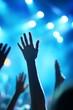 © BerkahStock - Silhouetted hands raised high at a concert, illuminated by bright stage lights.