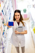 © Mediteraneo - Female pharmacist holding up a box of medication in the pharmacy.