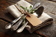© Mirivox - Silverware set with sage sprig tied on linen napkin, blank tag mockup, rustic wooden background.  Elegant table setting, representing Thanksgiving or fine dining