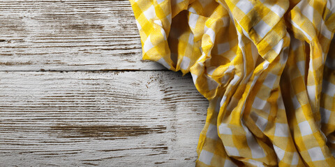 Fototapete - Yellow and white checkered fabric draped on whitewashed wooden surface, showcasing texture and free space for text or product placement, ideal for rustic or food-related designs