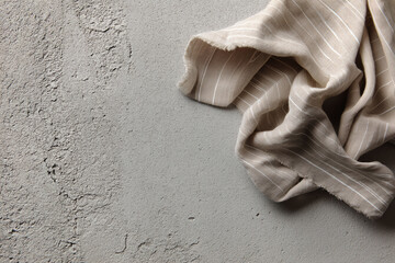 Fototapete - Beige linen fabric with thin stripes lies on gray textured surface, showcasing draped texture and ample free space ideal for text or logo placement