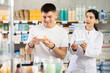 © JackF - Guy chooses pills in modern pharmacy. Female pharmacist helps with choosing a medicine