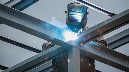Aufkleber - A medium closeup of sparks flying as a worker welds a support beam on the crane with a protective mask on and bright sparks contrasting against the gray metal structure