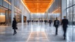 © John - Blurred motion of diverse business people walking through a modern building's bright, spacious lobby.