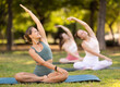© JackF - Group of girls in park practicing yoga outdoor. Active pastime together, performing exercise. Yoga lesson visitors perform padmasana, svastikasana. Girls practice sports during yoga workout in nature