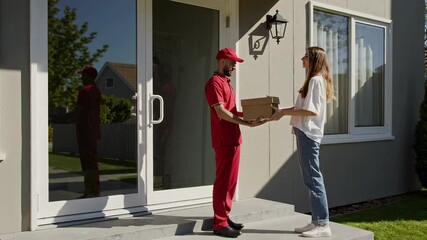 Aufkleber - Uniformed delivery person handing cardboard package to smiling homeowner, showcasing residential home delivery service on bright, sunny day