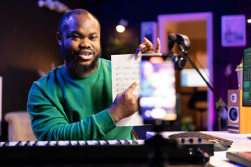 Poster - Singer producer showing musical sheet to explain notes on electronic keyboard, teaching how to play piano piano on a tutorial vlog in home studio. Performer musician presenting diatonic scale.