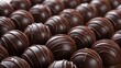 © TAMANNA JAHAN FARHAN - Many round, dark brown chocolate truffles are densely clustered together.