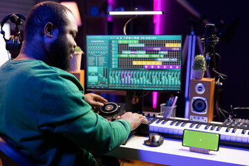 Poster - Male composer using mixing console and piano to edit tracks, having a greenscreen on smartphone. Musician producing new songs with mixing and mastering techniques in home studio.