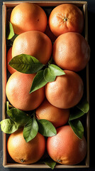Poster - Fresh grapefruits arranged in wooden box, surrounded by vibrant green leaves, create visually appealing display. bright orange color of fruit adds cheerful touch to any setting