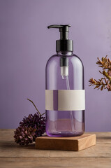 Poster - purple bottle with pump alongside dried flowers on wooden surface in a soft light setting