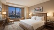 © Beatriz - Elegant hotel bedroom with city views, featuring a plush bed, cozy chairs, and a desk, bathed in warm light for a relaxing atmosphere.