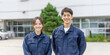 © shibadog - Oriental men and women in work clothes standing side by side smiling outdoors.