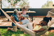 © Carlo Prearo - Multi-ethnic family relaxing together in garden hammocks