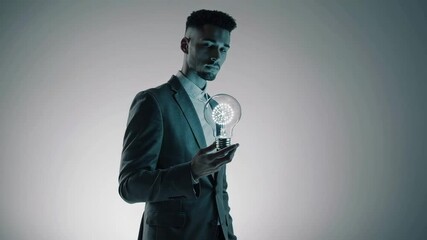 Poster - Businessman in a suit, isolated on a white background, contemplates an illuminated light bulb, symbolizing the generation of innovative ideas and strategic thinking in a corporate setting