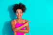 © deagreez - Smiling young woman in a vibrant sport bodysuit pointing to the side on a teal background