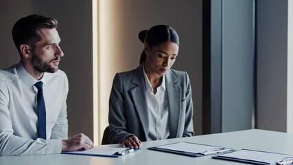Poster - Professional business partners working together, intently reviewing contract details and discussing strategic terms at modern office meeting table