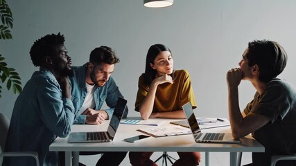Poster - Three diverse colleagues, including an african american man, are engaged in a focused discussion, analyzing charts and brainstorming ideas while seated at a table with laptops and documents