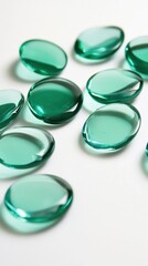 Poster - Serene Emerald Green Glass Gems on White Surface Close Up Macro Shot with Soft Lighting and Clean Background for Stock Photo