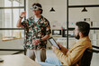 © AnnaStills - Medium shot of unrecognizable bearded man with disability holding tablet while looking at his coworker who testing VR headset and playing brand new VR game