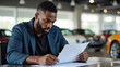 © AlgoCreative - man is focused on reviewing documents in car dealership, showcasing serious expression while seated at table