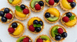 © IBEN - Delicious Assortment Of Mini Fruit Tartlets Topped With Glaze And Fresh Mint