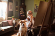 © Davor - Senior artist in wheelchair painting at home with dog by his side