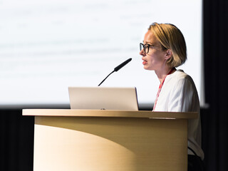 Wall Mural - female speaker giving a talk on corporate business conference. business and entrepreneurship event
