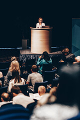 Wall Mural - female speaker giving a talk on corporate business conference. unrecognizable people in audience at 