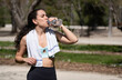 © VictorCanalesStudio - Young athletic woman drinking water from a bottle after training in a park on a sunny day