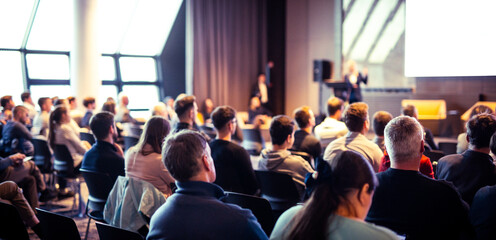 Wall Mural - speaker giving a talk in conference hall at business event. rear view of unrecognizable people in au