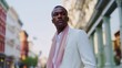 © fotofabrika - Stylish man in white suit and pink scarf poses confidently in urban setting during bright day
