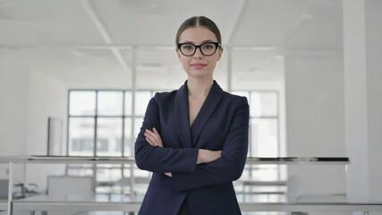 Poster - A professional woman wearing a suit and glasses confidently stands with her arms crossed, conveying a sense of authority.