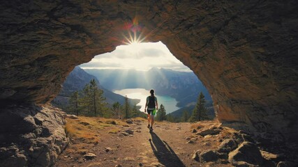 Poster - A woman stands in the entrance of a cave, gazing out at a serene lake.
