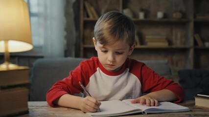 Poster - A young boy sitting at a table with a pen and paper, perfect for illustrations, stories or creative projects.