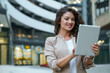 © Dorde - Successful Businesswoman Reading Digital Tablet While Standing Outdoors Near Contemporary Corporate Architecture With Bokeh Lights