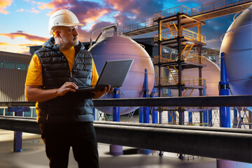 Poster - Industrial engineer with a laptop inspects equipment at a chemical plant during sunset. Scene relates to process engineering and industrial facility operations.